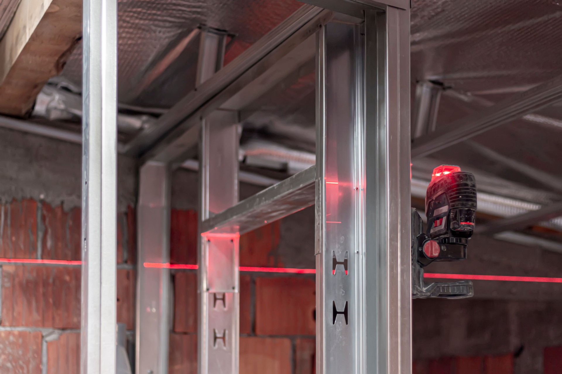 Using a laser to mark the outlines on the floor and transfer them to the walls and ceiling for accurate construction measurement and alignment.